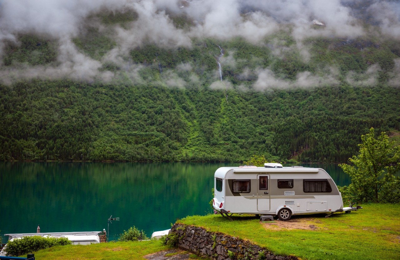 Campingvogn parkert ved vann. Foto.